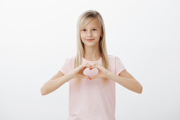 Free Photo lovely child showing heart gesture and smiling