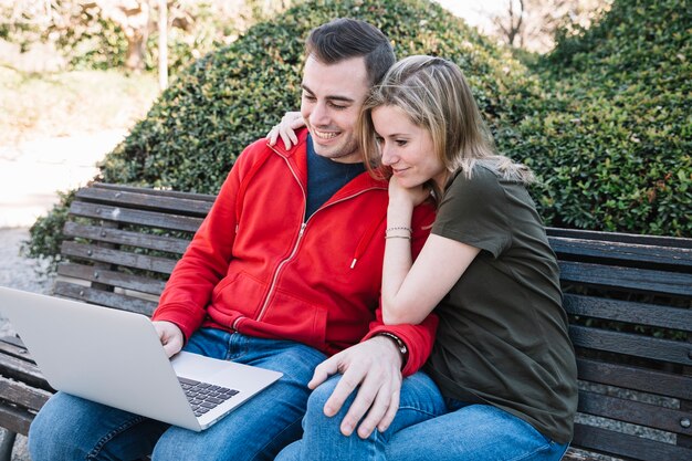 Lovely couple browsing laptop on bench