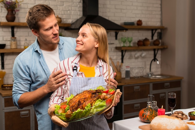 Lovely couple looking at each other and holding the thanksgiving turkey