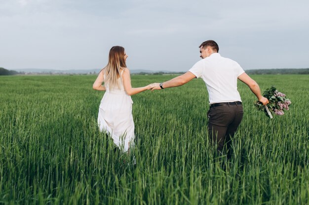 The lovely couple in love walking along field