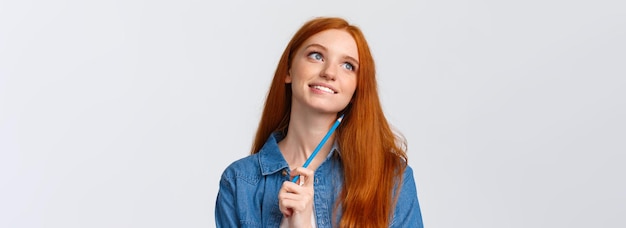 Free photo lovely and creative thoughtful dreamy smiling redhead woman looking up and thinking imaging somethin