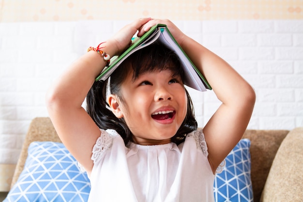 Free photo lovely girl joyful with a book on head