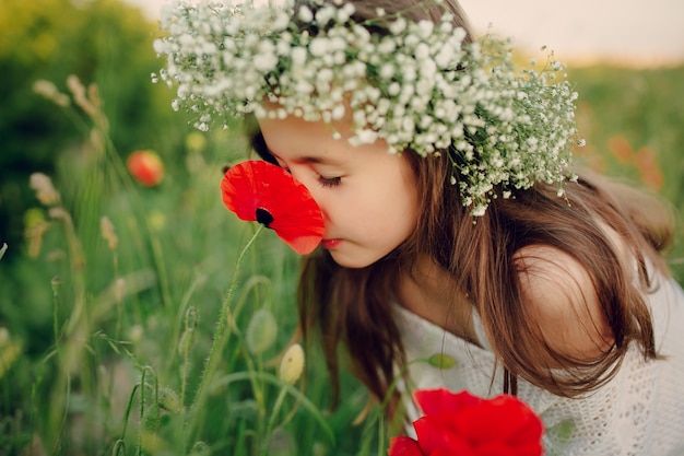 Lovely little girl smelling a poppy