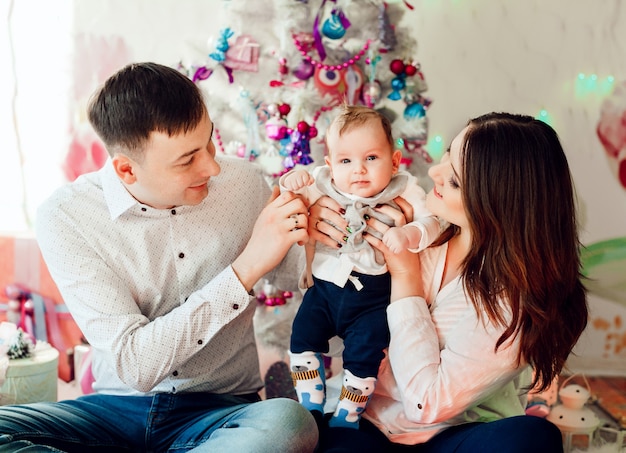 Free Photo lovely parents play with little daughter before a pink christmas tree 