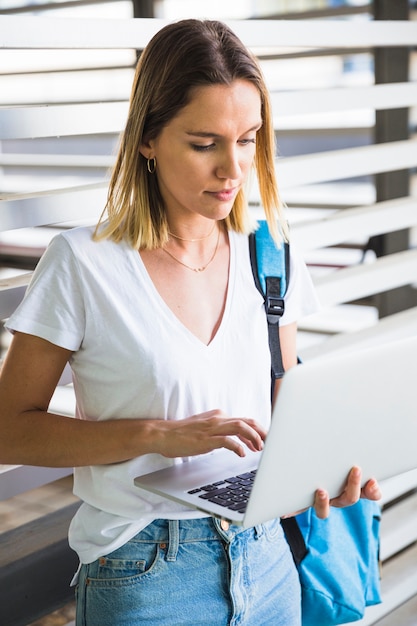 Lovely woman browsing laptop near wall