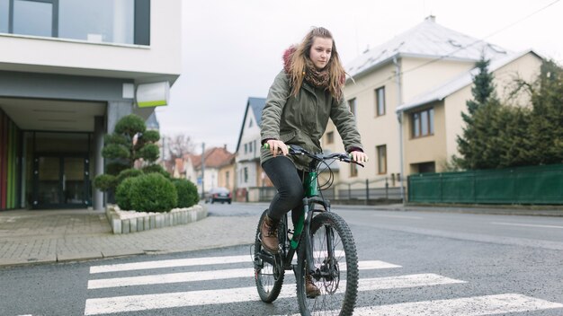 Lovely woman crossing street on bicycle