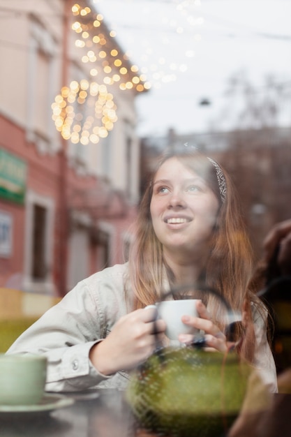 Free photo lovely woman holding coffee through window