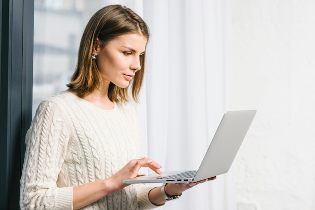 Free photo lovely woman using laptop near window