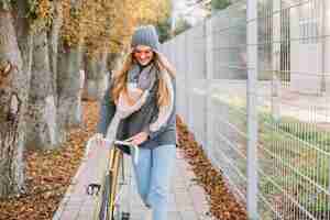 Free photo lovely woman walking with bicycle near fence