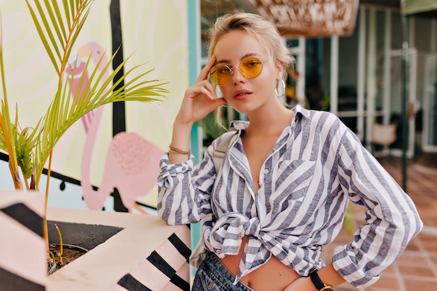 Free photo lovely woman with bare skin and fantastic smile in stripped shirt and round glasses posing