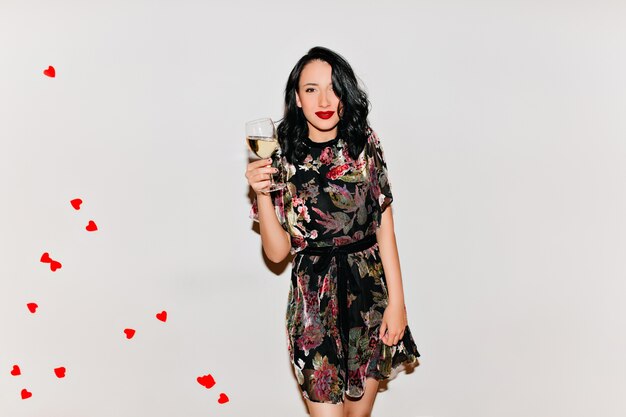 Lovely woman with black curly hair holding glass of champagne