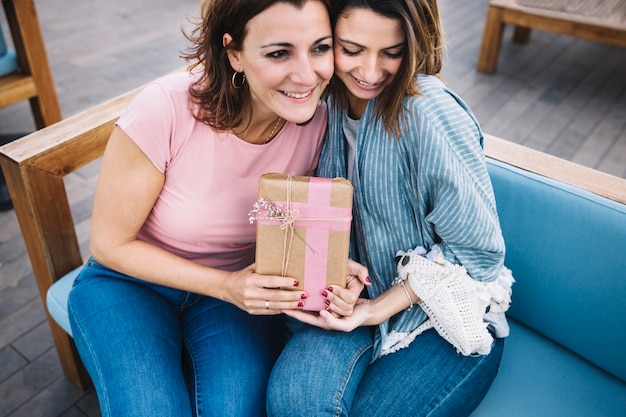 Free photo lovely women with present on couch