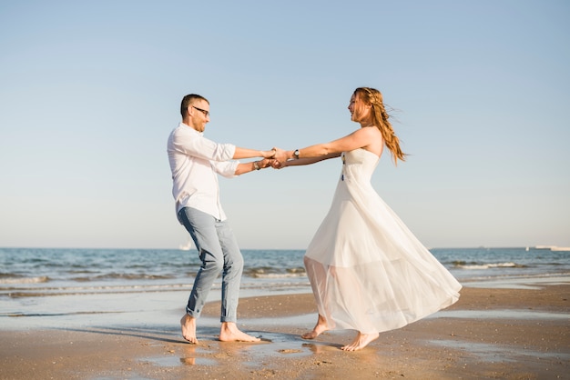 Free photo lovely young couple dancing together near the seacoast at beach