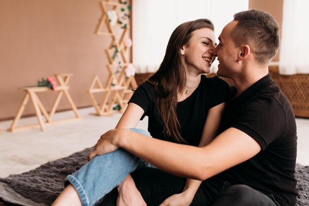 Lovely young couple dressed in casual style sits on the floor 