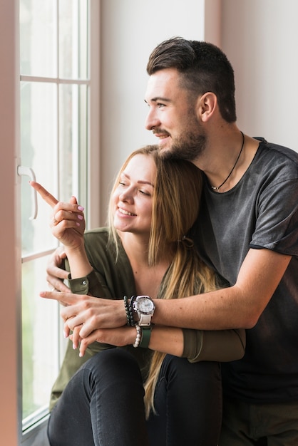 Lovely young couple sitting on window sill looking outdoors