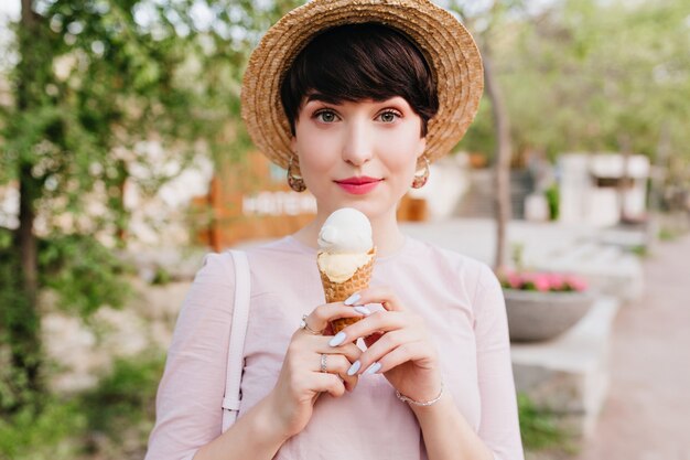 Free Photo lovely young woman in vintage outfit with elegant manicure walking on the street and eating vanilla ice cream with pleasure