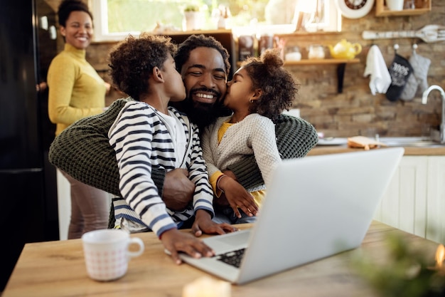 Loving African American kids kissing their father at home