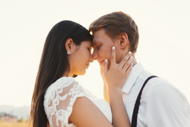 Loving couple dressed in white, ready to kiss outdoors with clos