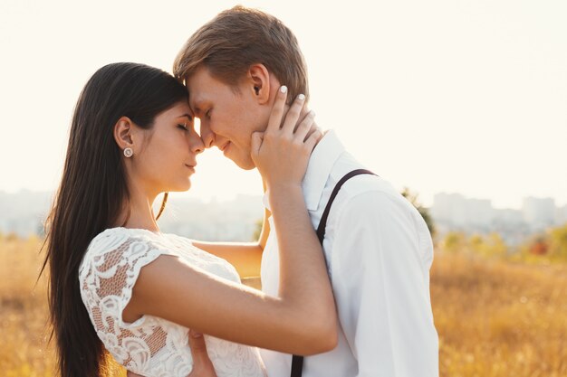 Loving couple dressed in white, ready to kiss outdoors