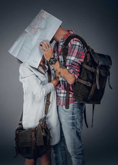 Free photo loving couple ready to travel with backpacks and a map. a man kissing a woman.