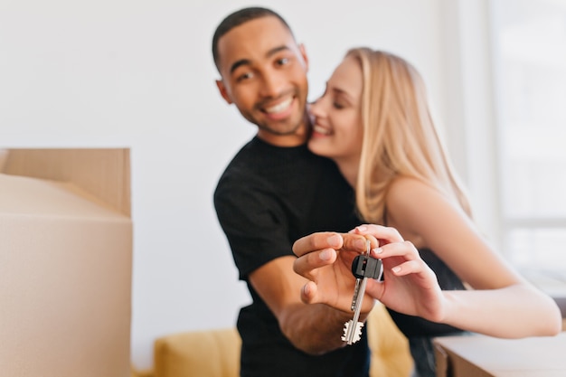 Loving couple showing keys of new house, going to move to new apartment, bought flat, packing cardboard boxes, relocating.