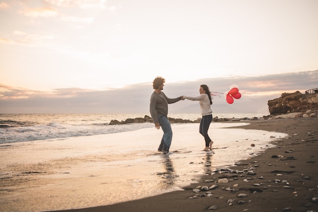 Free photo loving couple throwing hands and her with balloons in hand