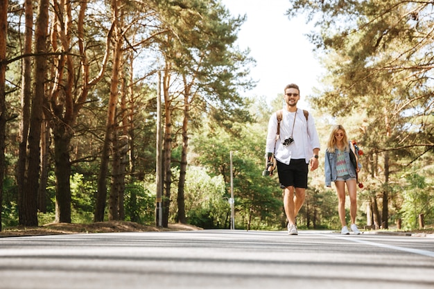 Loving couple walking with skateboards outdoors.