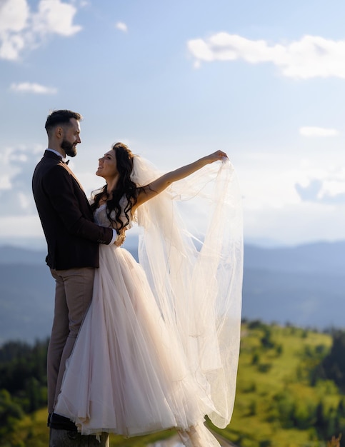 Loving couple in wedding outfits posing on nature in mountains