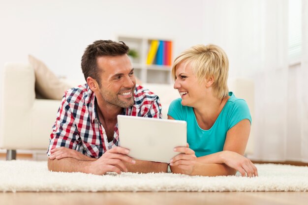 Loving couple with digital tablet on carpet