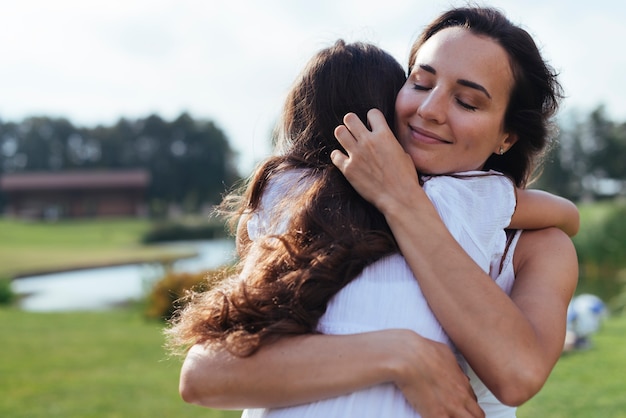 Loving mother hugging daughter outdoors