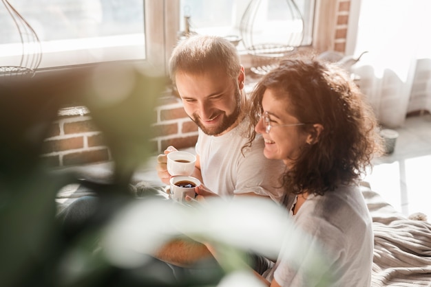 Loving smiling young couple holding cup of coffee in hands