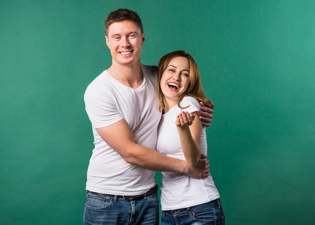 Loving young couple looking to camera against green background