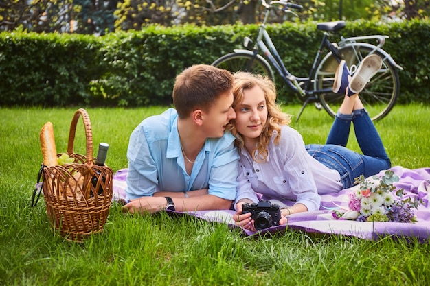 Free photo loving young couple photo shooting and relaxing at a picnic in a park.