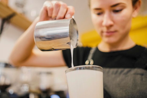 Free photo low angle of barista pouring milk in glass