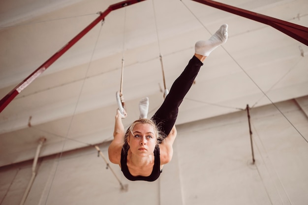 Low angle blonde woman training on gymnastics rings