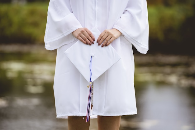 Free Photo low angle closeup shot of a female graduate wearing a white cap and gown