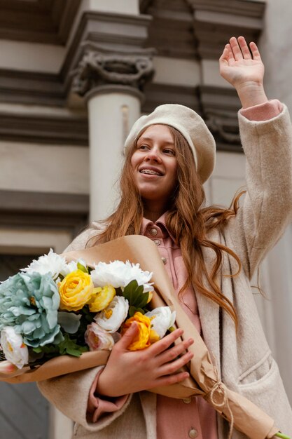 Low angle of elegant woman outdoors holding bouquet of flowers in the spring