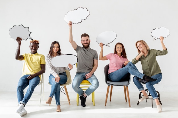 Free Photo low angle friends on chairs with chat bubbles