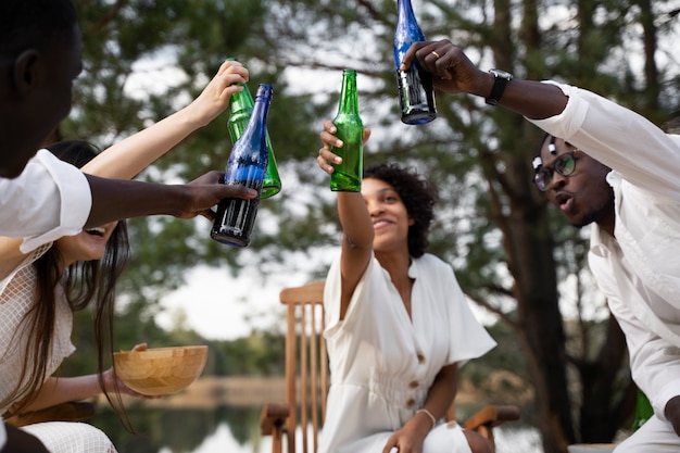 Free photo low angle friends clinking bottles