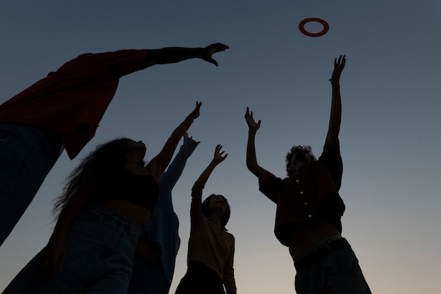 Free photo low angle friends silhouettes jumping at sunset