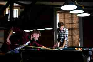 Free photo low angle guys playing billiard at club