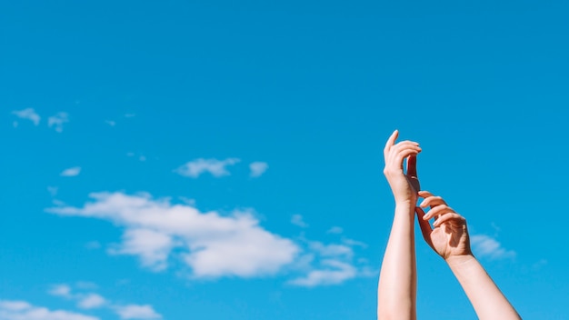 Low angle of hands raised up with sky and clouds