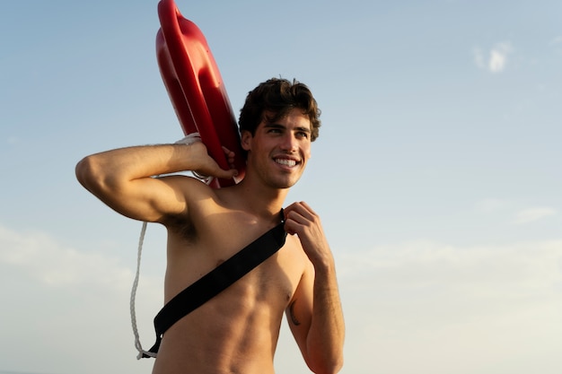 Free photo low angle lifeguard holding lifesaving buoy