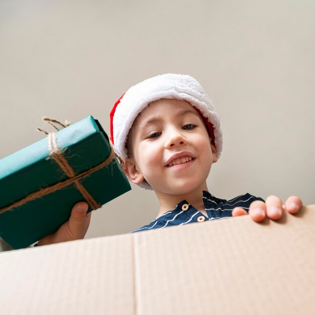 Low angle little boy holding a gift