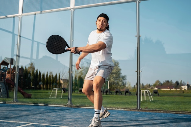 Low angle man playing paddle tennis