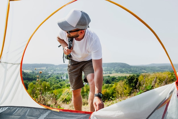 Free photo low angle man pull tent zipper