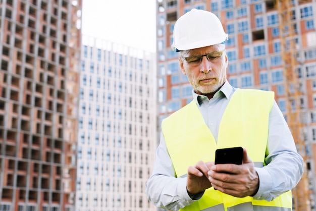 Free photo low angle old man looking at smartphone