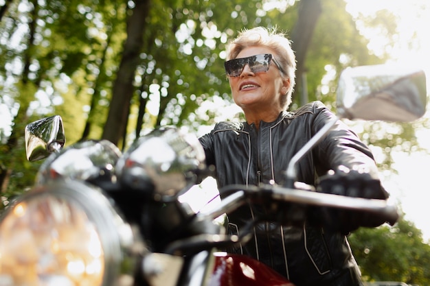 Free photo low angle old woman with cool motorcycle