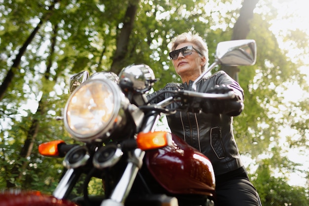 Low angle old woman with cool motorcycle