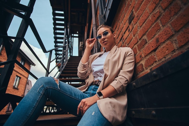 Free Photo low angle photo of casual cheeky woman in sunglasses and denim at back yard.